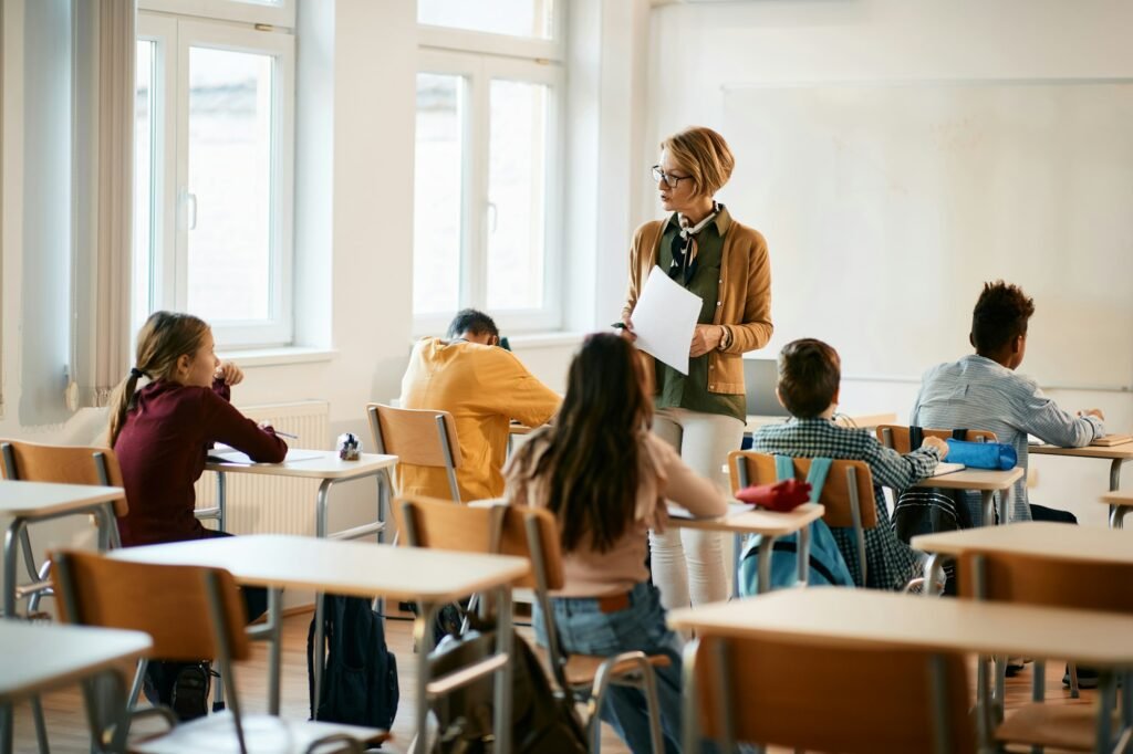 Mature teacher holding a class to group of school kids at primary school.